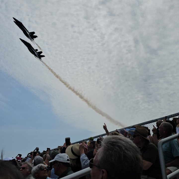 Two Blue Angel Jets flying over bleachers filled with spectators