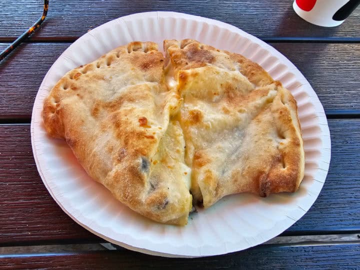 Calzone on a paper plate near a glass