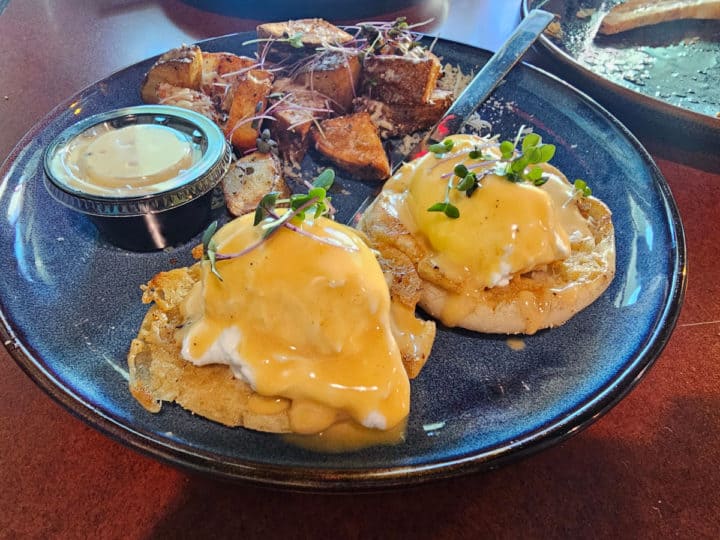 eggs benedict with potato's on a blue plate. 