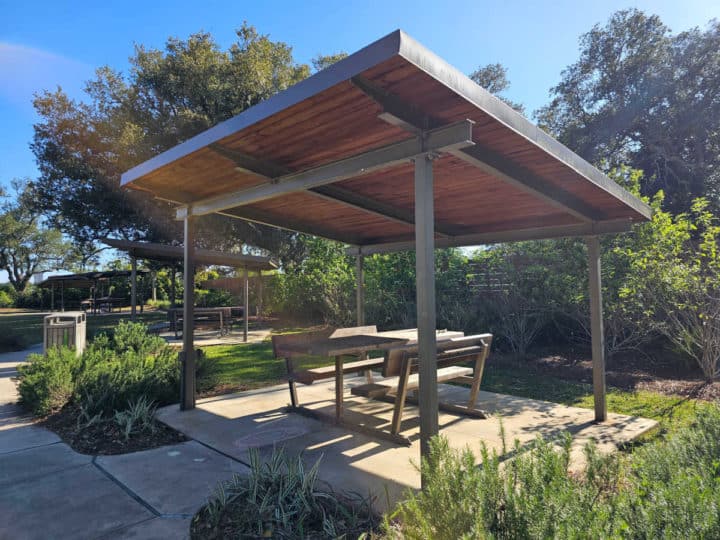 Covered picnic shelter with picnic table surrounded by greenery