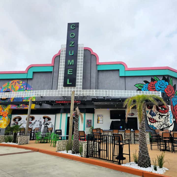 Cozumel lighted sign on a restaurant with multiple painted skull murals