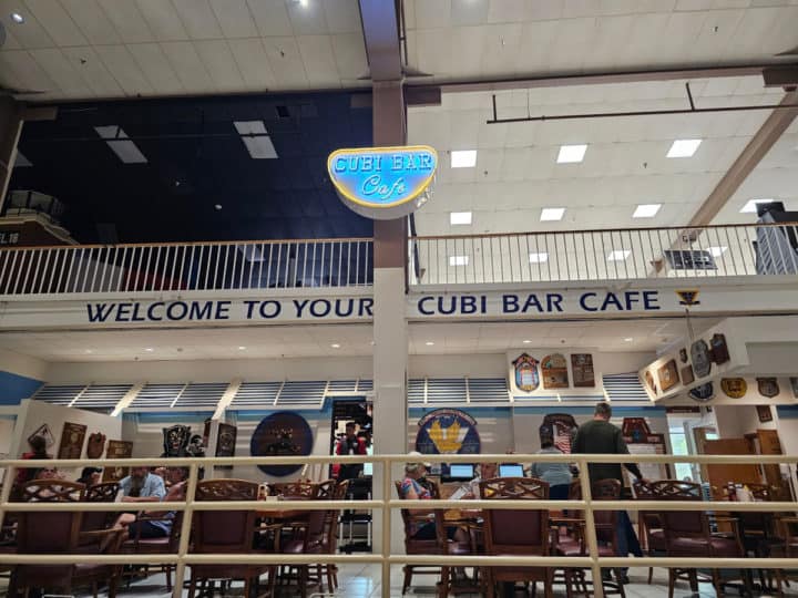 Welcome to Your Cubi Bar Cafe sign above tables and chairs