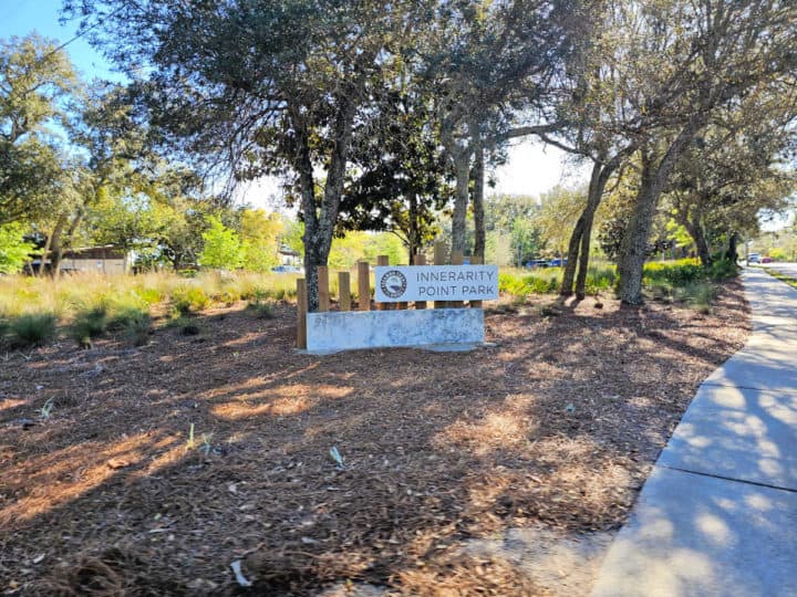 Innerarity Point Park entrance sign by trees and a concrete walkway