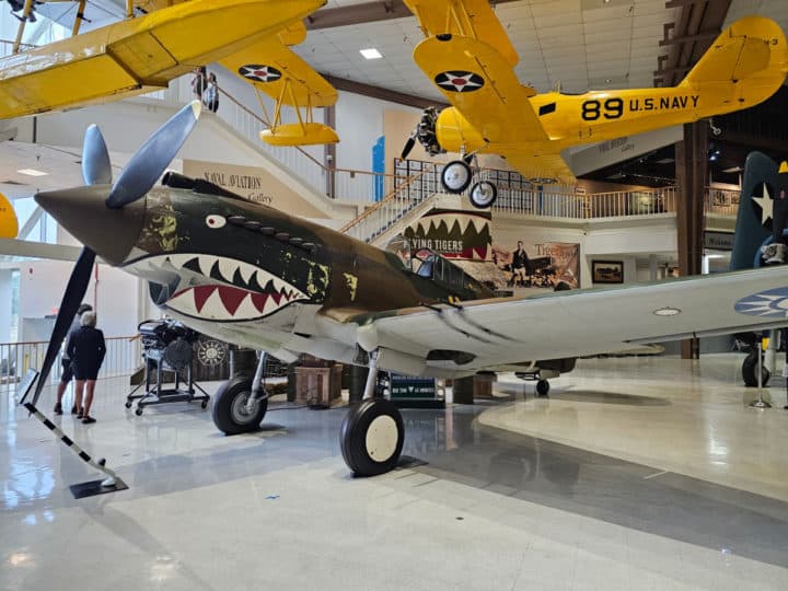 Black flying tiger plane on the floor with yellow planes hanging from the ceiling. 