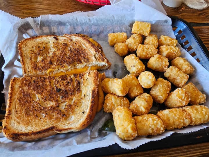 Grilled cheese and tater tots in a paper lined basket
