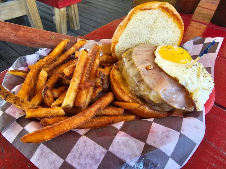 Hawaiian burger with fried egg on a checkered basket with fries