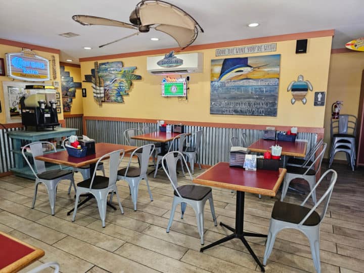 indoor seating with tables and chairs, swordfish picture on the wall, bushwacker machine in the corner, and fan on the ceiling
