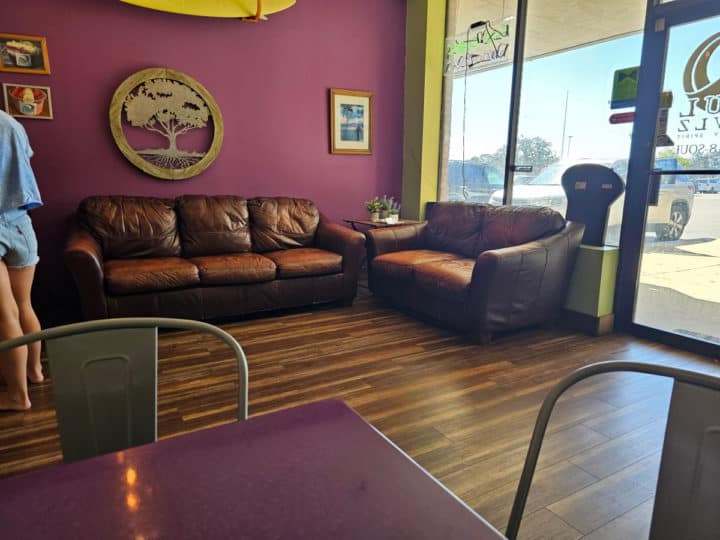 purple walls with tree art, two leather couches, and a small table with metal chairs 