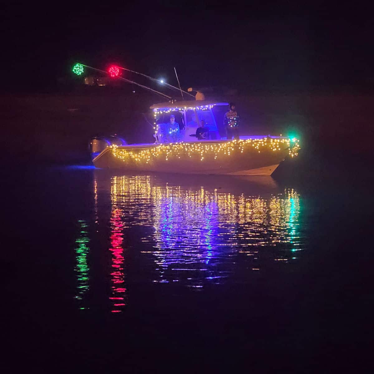 Boat decorated in holiday lights reflecting on the water