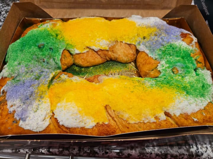 King cake with green, gold and purple sprinkles in a Gambino's Bakery box