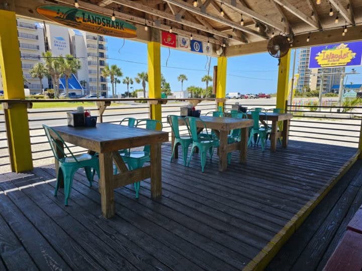outdoor tables and chairs on an outdoor deck with views of the Islander Food Shack sign and hotels