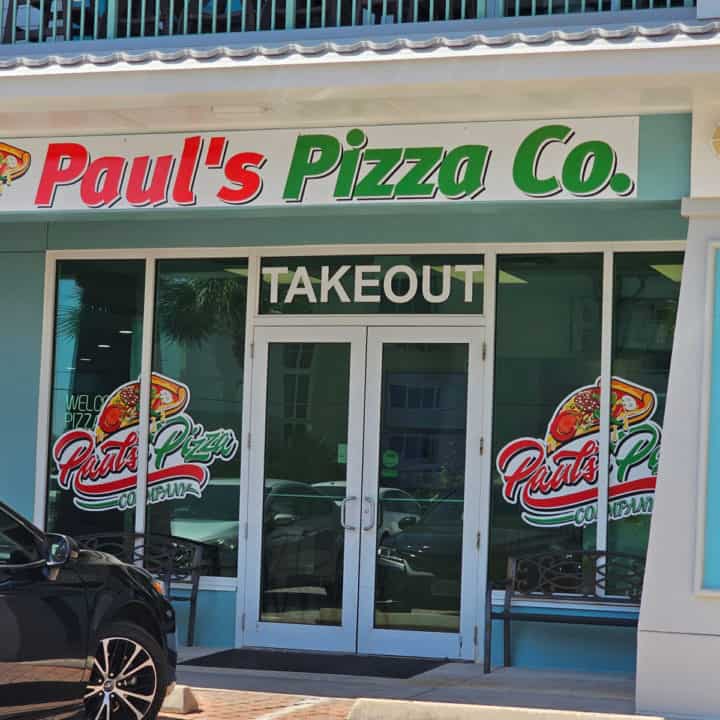 Pauls Pizza Co. sign over a glass entrance door with takeout and the Paul's Pizza Co logo