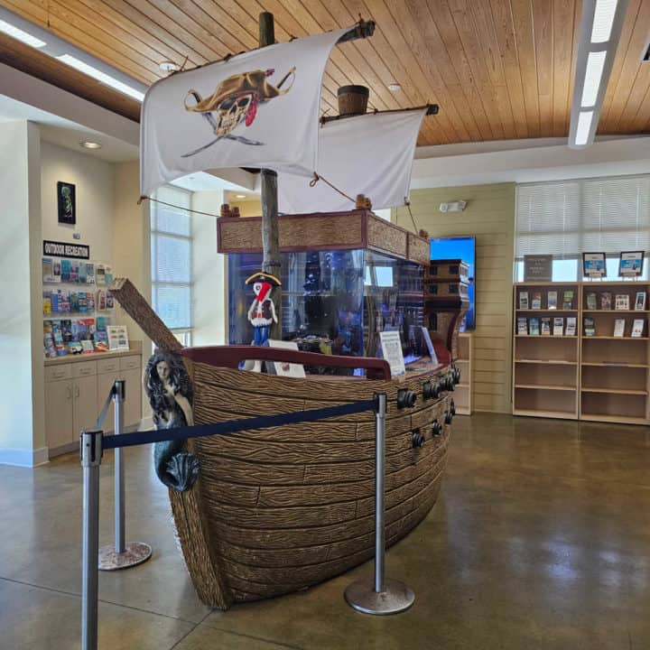 Pirate ship fish tank in the middle of the room with brochures on the back walls