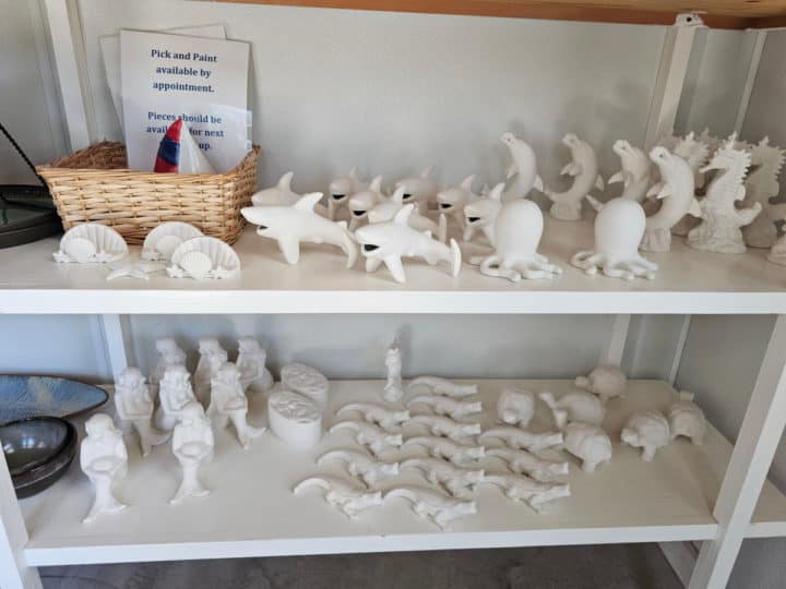 white marine pottery pieces on shelves with a pick and paint sign 