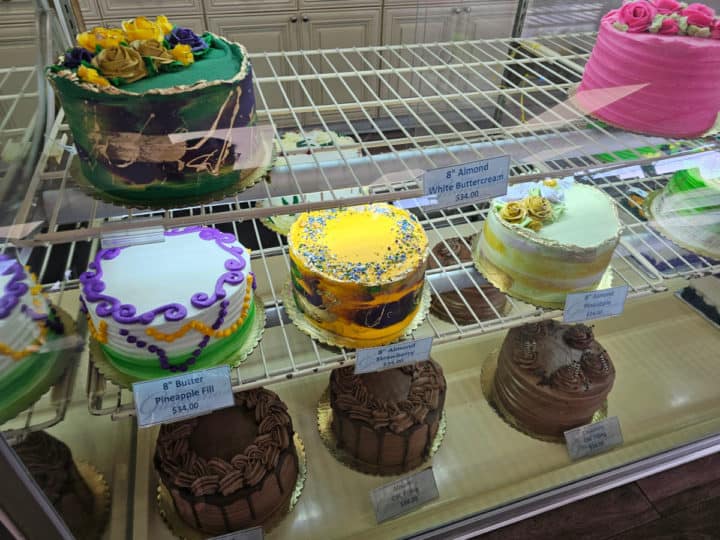 colorful cakes in a bakery display case with price tags