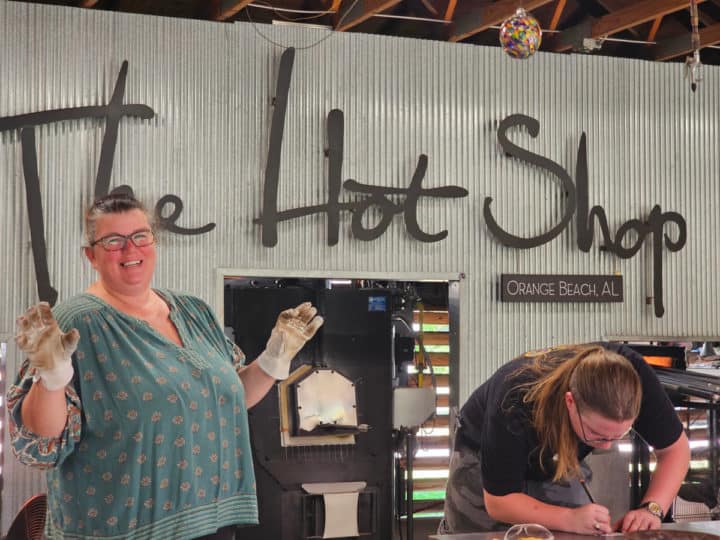 Tammilee standing with white gloves on near a sign for The Hot Shop orange Beach