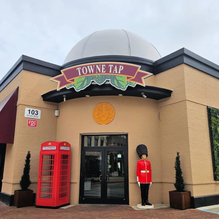 Towne Tap sign with leaves over a double door with a British red telephone box and British Royal soldier statue. 