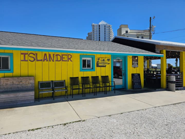 Bright yellow building with Islander printed on the side of it. chairs lined up near the door