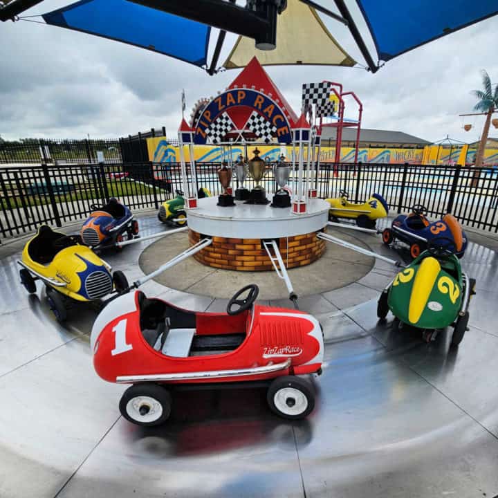 multiple kids cars in a circle near a sign that says Zip Zap Race with trophies under it
