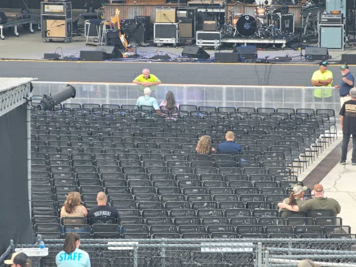 rows of black folding chairs in front of a stage with people in some of the seats