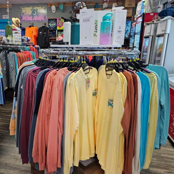 t-shirts on a rack with water bottles above