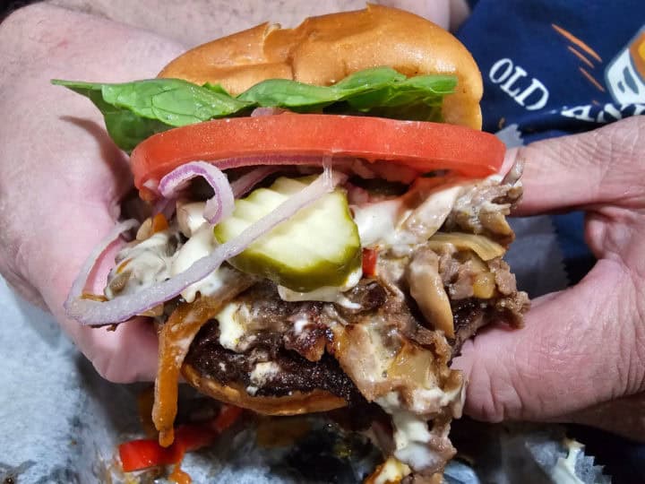 Cheeseburger with cheese steak being held