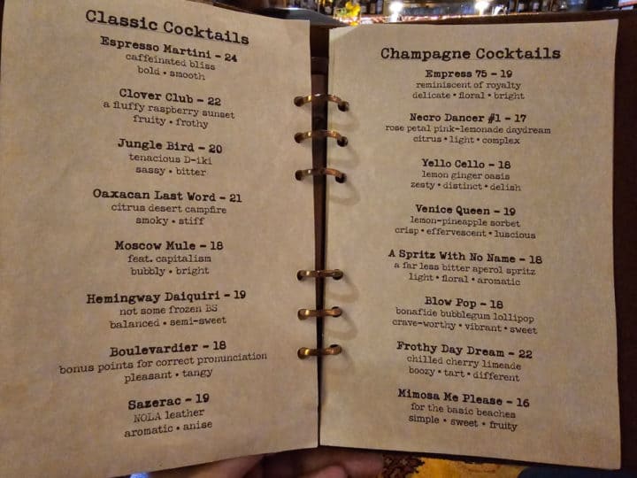 two pages of cocktail menu in a leather bound menu book