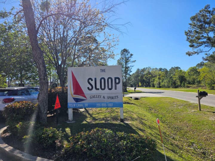 The Sloop entrance sign with trees in the background