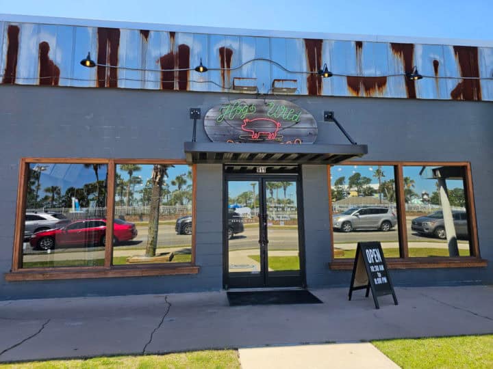 Hog Wild BBQ exterior with mirrored windows, neon sign, and hours sign