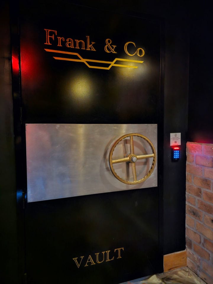 bank vault door with Frank & Co vault printed on it next to an electronic keypad
