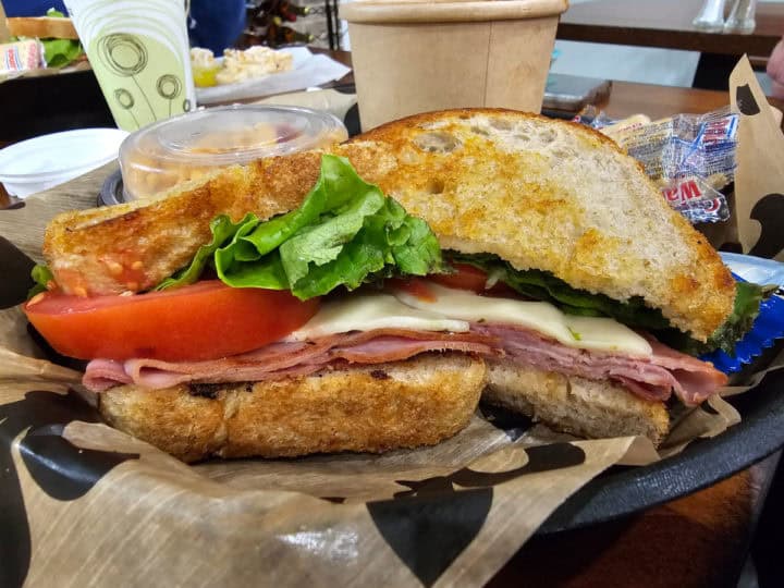 ham and swiss sandwich with tomato and lettuce in a paper lined basket