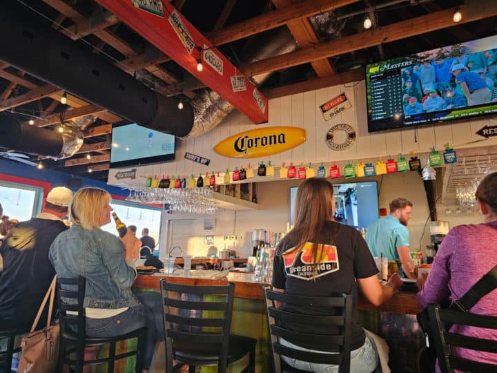 indoor bar with a tv over it and people sitting on bar chairs