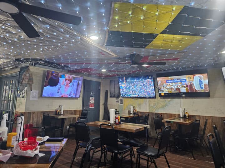 indoor seating with tables and chairs near TVs and lights on the ceiling