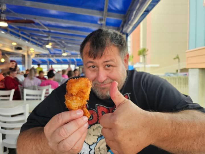 John holding a coconut shrimp and giving it a thumbs up.