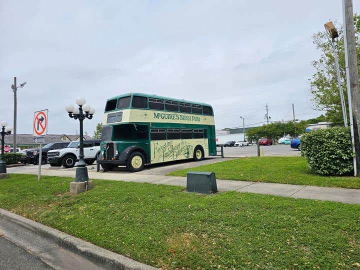 green double decker bus with McGuire's printed on the side in a parking area