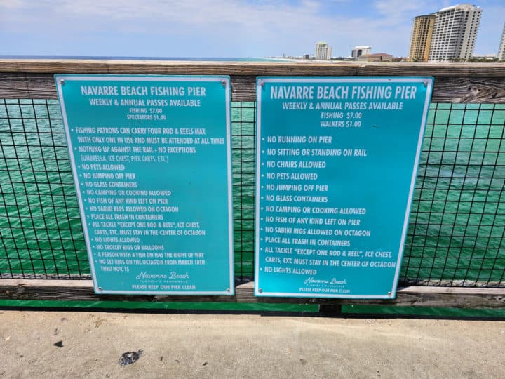 list of pier rules on two blue boards attached to the Navarre Beach Pier