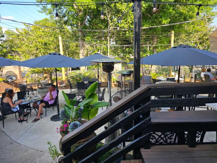 outdoor seating with umbrellas over the tables and greenery