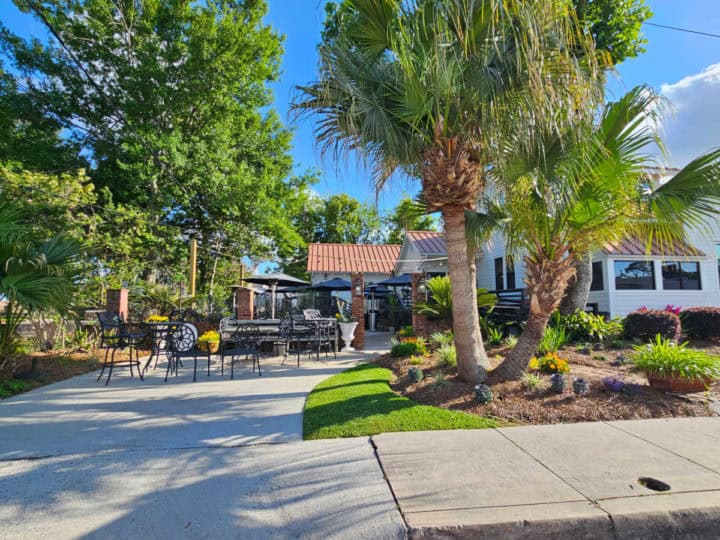 outdoor seating area next to a white building with palm trees