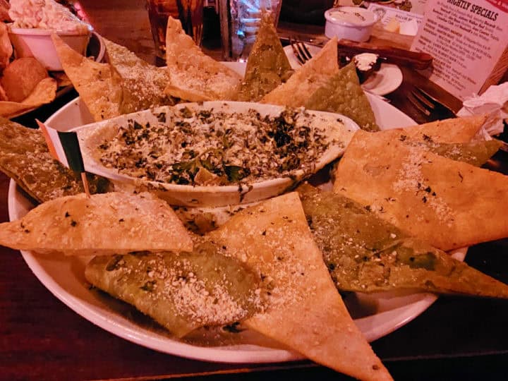 spinach artichoke dip surrounded by large white and green tortilla chips