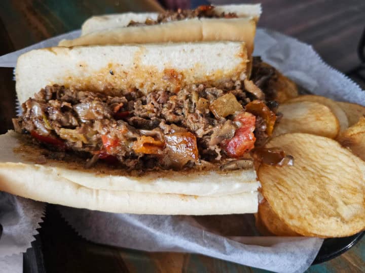 cheesesteak sandwich on a roll with chips