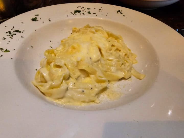 long pasta noodles covered in cream sauce on a white plate