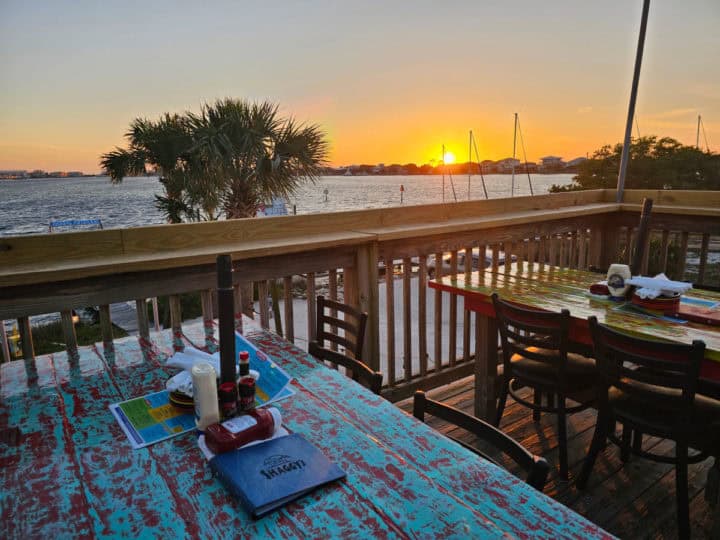 sunset over the water from a deck with tables with Shaggy's menus on them