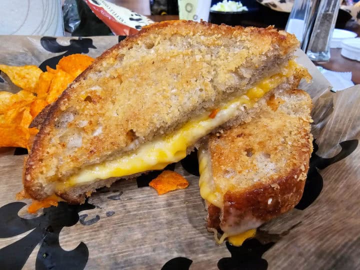 grilled cheese sandwich next to chips in a paper lined basket