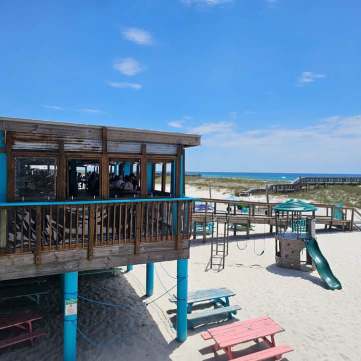 restaurant looking out over the water with picnic tables below it