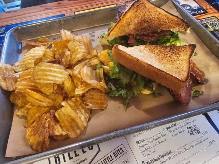 BLT sandwich next to chips on a paper lined tray and Bill E's Menu