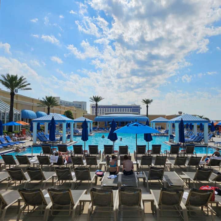 Chairs lined up before a swimming pool and cabanas on a blue sky day