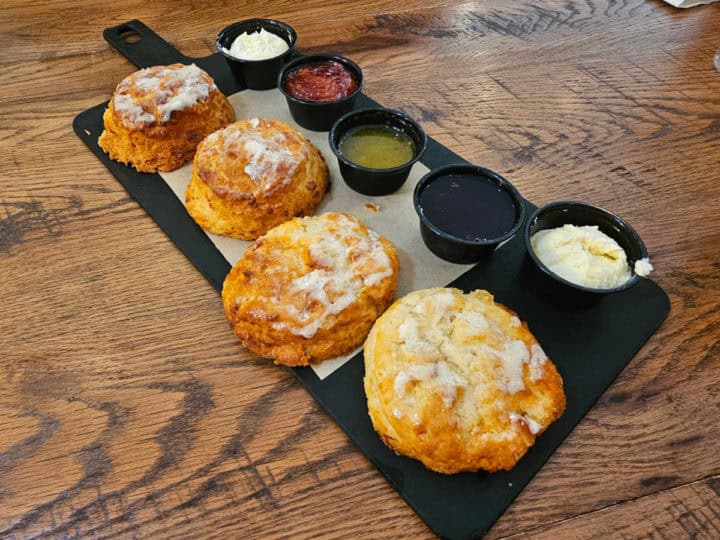 four biscuits on a board with jams and jellies