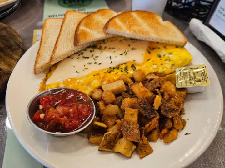 Cheese omelet with potatoes and white toast on a white plate