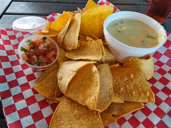 chips and queso on a red and white checkered paper lined basket