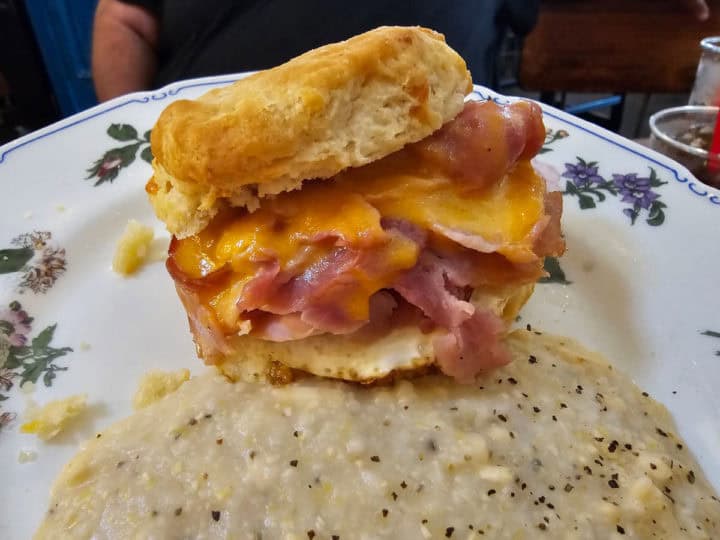 ham, egg and cheese biscuit on a floral plate with gouda grits